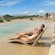 A couple in chaise lounges clinking glasses while relaxing in a shallow pool right on the beach